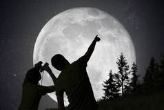 人们在夜空中观察星星的轮廓。月球的背景.