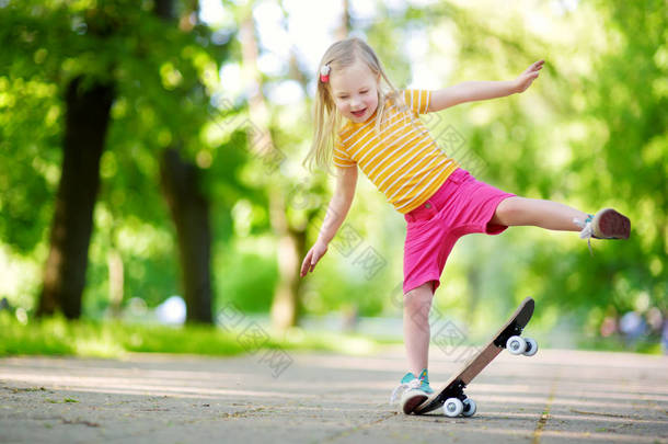 漂亮的小女孩学习玩滑板 