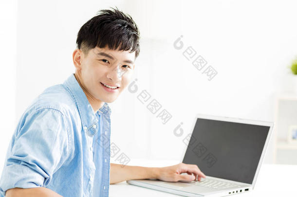 与<strong>笔记本电脑</strong>的亚洲年轻男人微笑着
