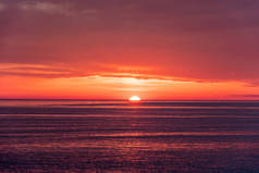 美丽的红色和橙色的日落在海面上。太阳从海上下来.