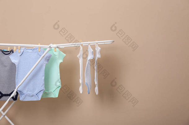 不同可爱的婴儿挂在衣服线上的米色背景，文本的空间。洗衣日
