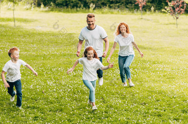 快乐的家庭与两个孩子玩, 在公园里一起跑步