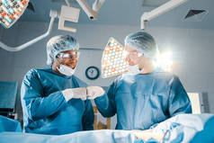 护士和外科医生在制服做手势和微笑在手术室 