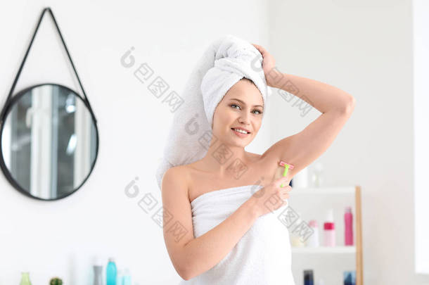 浴室里美丽的年轻妇女剃须腋窝