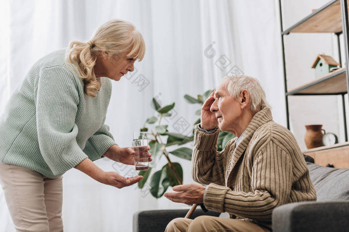 用拐杖给老人吃药和杯水的老年妇女
