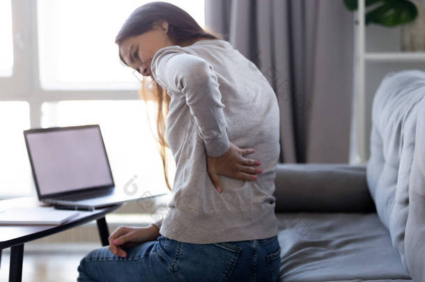 在家中久坐电脑后感到背痛的年轻女子