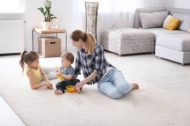 妈妈带着可爱的小孩子坐在舒适的地毯上在家