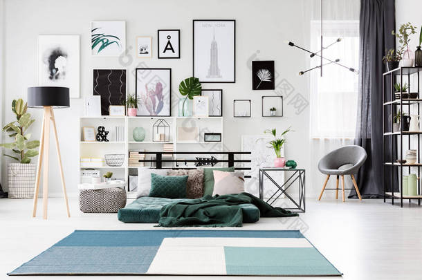 蓝色地毯附近绿色床垫和灯在宽敞的卧室内部与扶手椅和画廊