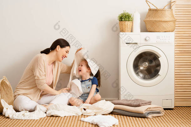 在家里洗衣服的时候，漂亮的年轻<strong>妇女</strong>和小女孩的小助手们都在开心地笑着.                               