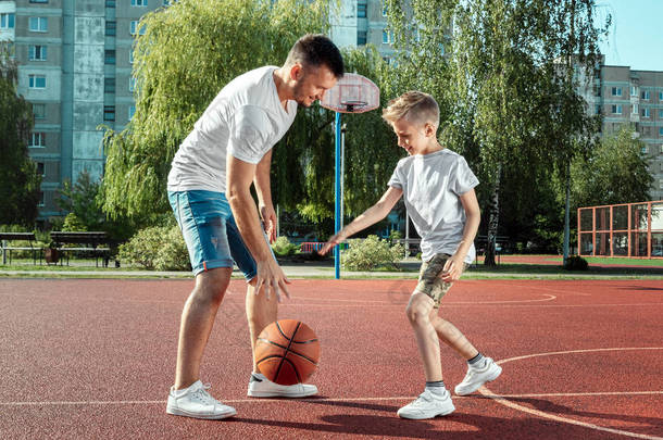 父亲和儿子一起在篮球场打篮球。父亲花<strong>时间</strong>与孩子，<strong>运动</strong>的生活方式，训练，休息，度假.