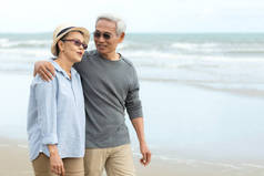 亚洲人的生活方式是老年夫妇在海滩上快乐地散步和放松。退休假期和暑假后的旅游、老年家庭旅行、休闲和活动.