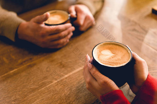 裁剪的看法的男人和年轻女子拿着杯子与咖啡在咖啡馆 