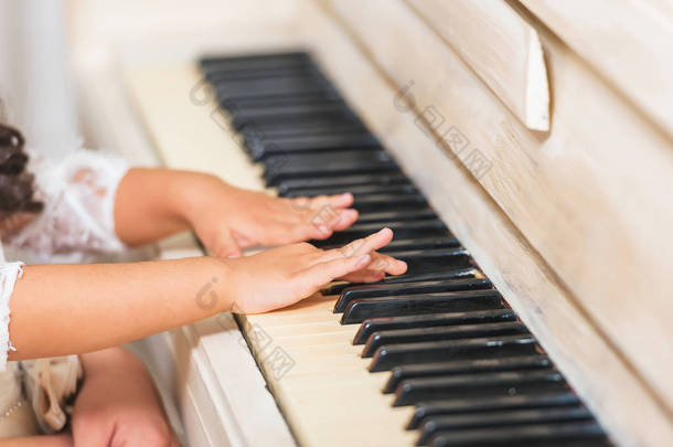 复古经典钢琴。白色乐器。黑色和白色的钥匙。孩子们的手放在钥匙上。抱着孩子的妇女.