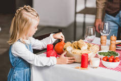 感恩节，可爱的女儿拿着盛有玉米和南瓜的碗 