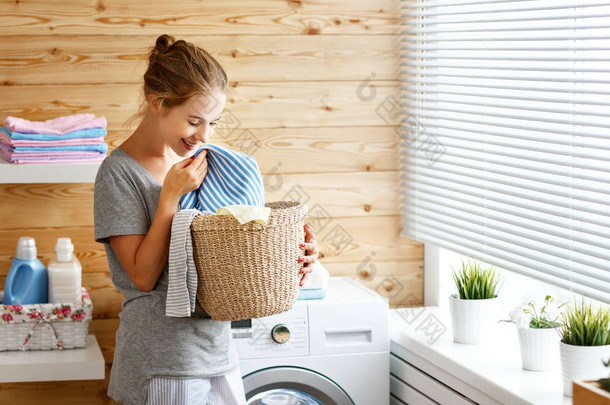 有洗衣机的洗衣房里快乐的家庭主妇 