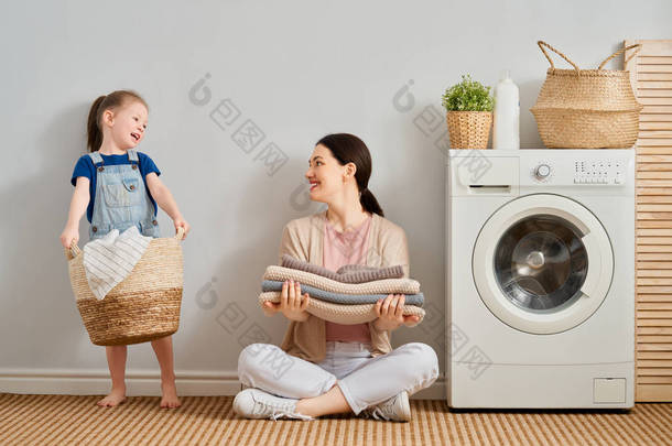 在家里洗衣服的时候，漂亮的年轻妇女和小女孩的小<strong>助手</strong>们都在开心地笑着.                               