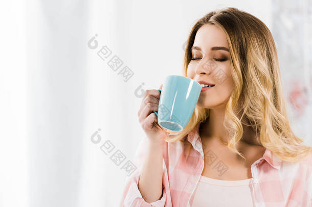 迷人的年轻女子在粉红色的衬衫喝咖啡闭着眼睛