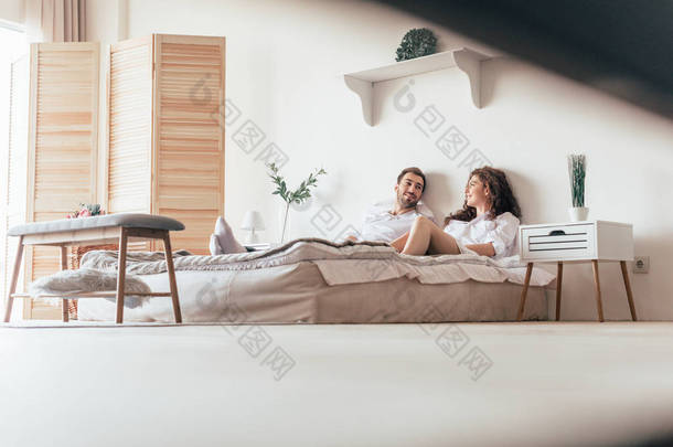 微笑的夫妇躺在床上，看着对方
