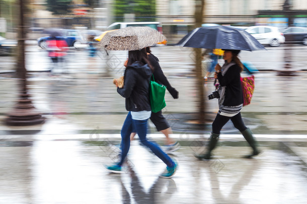 年轻人在运动模糊走在多雨的城市