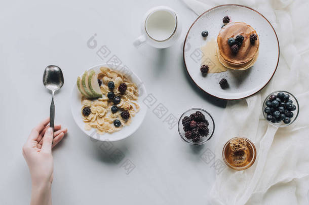 人拿着勺子和新鲜健康的早餐在灰色的拍摄