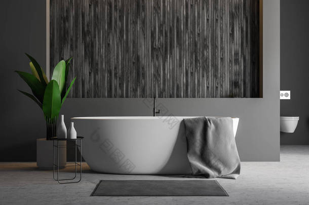 现代化的浴室<strong>内饰</strong>有灰色和木墙、水泥地板、白色浴缸和毛巾, 附近有地毯和卫生间。3d 渲染