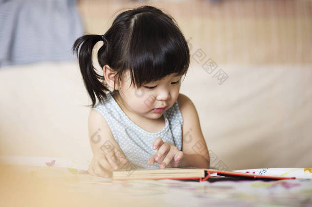 迷人可爱的亚洲孩子集中在阅读本书