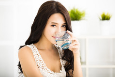 轻松自在的年轻微笑的女人喝着洁净的水