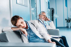 疲惫的男女医生睡在医院走廊的沙发上 