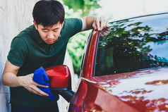 年轻亚洲人在统一清洗与在户外洗车.