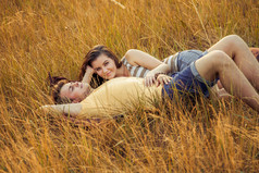 爱的情侣躺在秋季公园的花卉领域。享受, 放松和 r