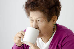 亚洲高级女人靠近窗口与温暖的轻喝一杯茶