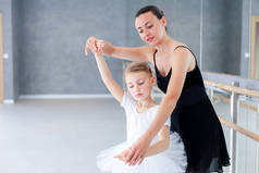 芭蕾舞老师和小芭蕾舞演员在古典舞蹈学校实习. 成人舞蹈教练正在教小女孩做儿童舞蹈练习.