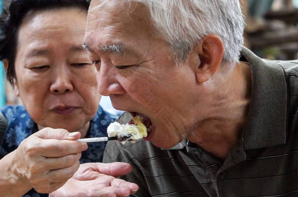 爱吃冰淇淋的一对亚洲老夫妻快乐地在户外约会