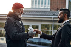 商人在街上给无家可归的乞丐钱