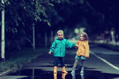 男孩和女孩在公园/秋季公园散步，儿童雨衣，家庭