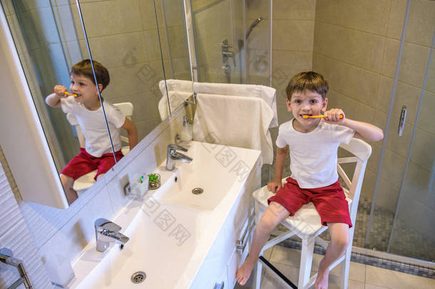 一个可爱的小男孩正在用牙刷刷牙。在他穿着的一件纯白色T恤上，你可以做一个广告题词。儿童健康、医药的概念