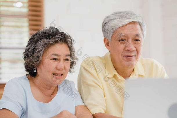 亚裔老年夫妇使用笔记本电脑与医生在客厅里谈论医学信息，夫妻俩一边躺在家里的病床上一边。家庭家庭健康概念.