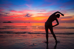 女人在附近海洋沙滩上的行使在日落时做在泰国