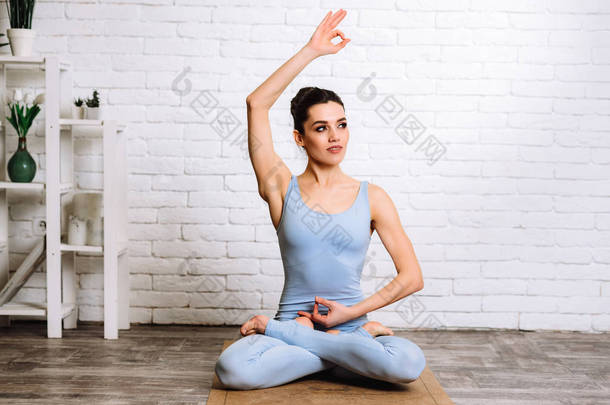 年轻的瑜伽女子练习瑜伽的概念。 穿蓝色运动服的女孩在垫子上做普拉提运动