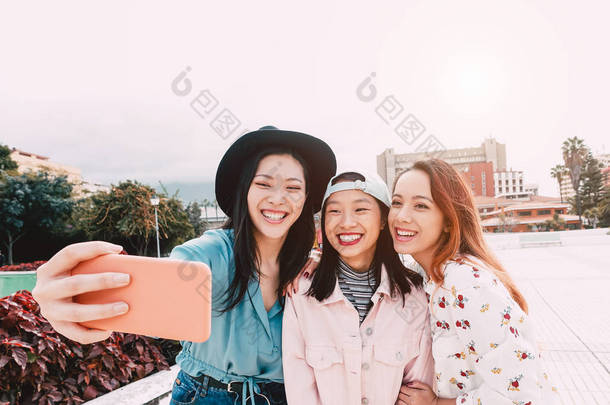 快乐的亚洲女孩采取自拍与移动智能手机户外 - 年轻的时尚青少年有乐趣与新技术应用程序 - 人，社会，媒体，友谊，技术和<strong>青年</strong>生活方式的人的概念