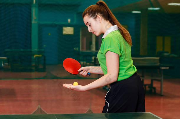 一个15岁的白种人黑发女孩在乒乓球比赛中做一个球。乒乓球