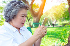 奶奶或上了年纪的妇女练习使用智能手机玩社交媒体。外婆对高科技感到困惑。老亚洲女人的视力最近不清楚。她被人看到很久了复制空间