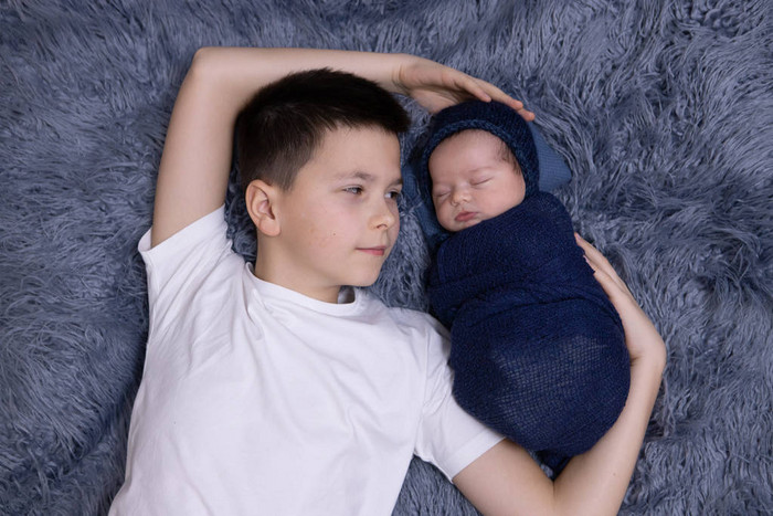 小弟弟抱着她刚出生的婴儿幼儿遇到新的兄弟