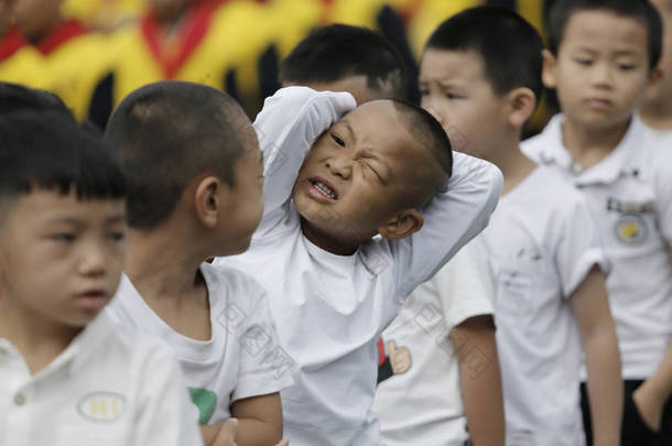 2 0 1 8年 8月 2 7日, 在中国西南贵州省贵阳市一所小学, 一名年轻学生和其他学生在参加新学期的升旗仪式时做鬼脸. 