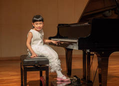 亚洲小女孩与大钢琴在学校的音乐会.