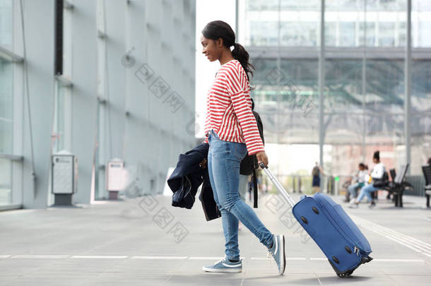 年轻黑人女子提着手提箱在<strong>机场</strong>行走的全长侧像