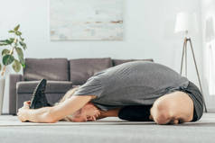 运动员在运动服运动和伸展瑜伽垫在家里的侧视图