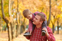 父子两人在秋城公园玩耍和玩耍。他们摆姿势, 微笑着, 玩耍。明亮的黄色树.