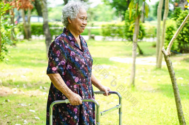 在节日快乐的情况下，亚洲年长或年老的老妇人在公园散步时使用健康的步行者 