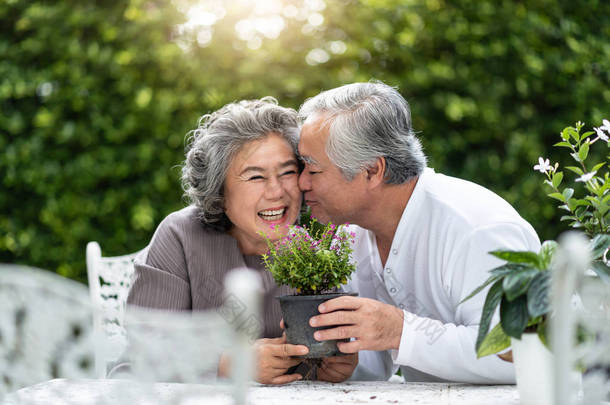 亚洲老人亲吻妻子的肖像。老夫妇享受与种植花在花园里。退休.